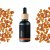 Schwarze Glasflasche mit Holzverschluss, die ätherisches Bio-Weihrauch-Öl enthält, umgeben von orangefarbenen Stücken Weihrauchhharz auf weißem Hintergrund