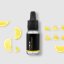 BIO lemon essential oil in black glass bottle with dropper surrounded by fresh yellow lemon slices on white background